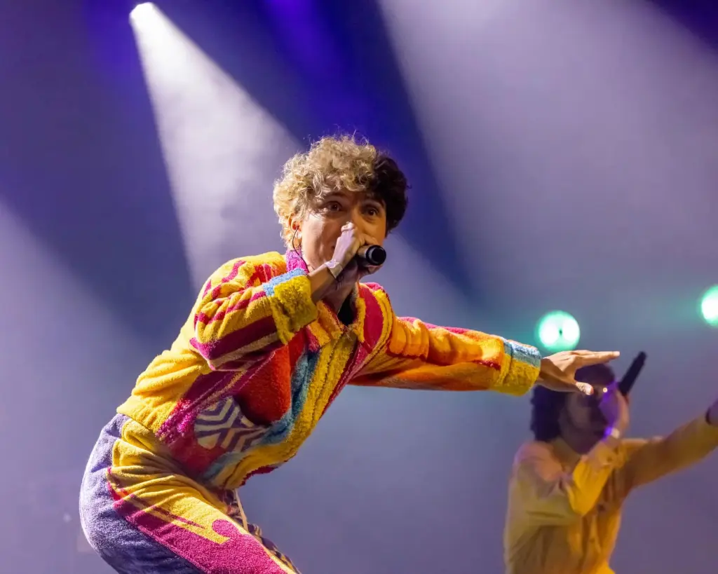 Babs op de beat staat in de spotlights op een podium en zingt in een microfoon. Ze draagt een kleurige outfit met gele, rode, roze en paarse kleuren. Op de achtergrond staat haar broer die ook in een microfoon zingt.