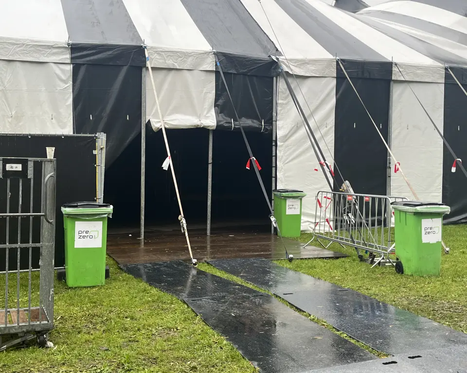 Festivaltent met rijplaten op het gras bij de ingang van de tent.