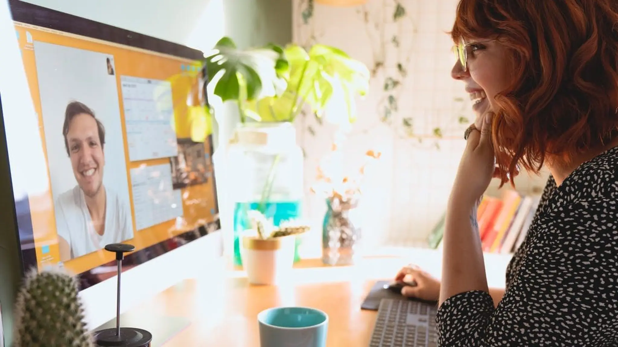 Een vrouw achter een beeldscherm die een online vergadering bijwoont.