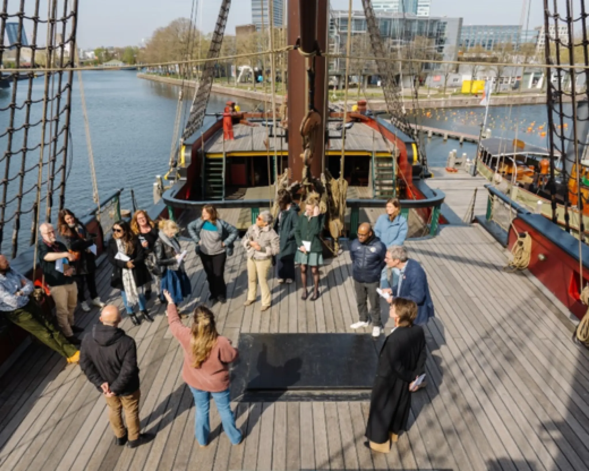 Cursisten staan in een cirkel op het dek van het VOC-schip Amsterdam.