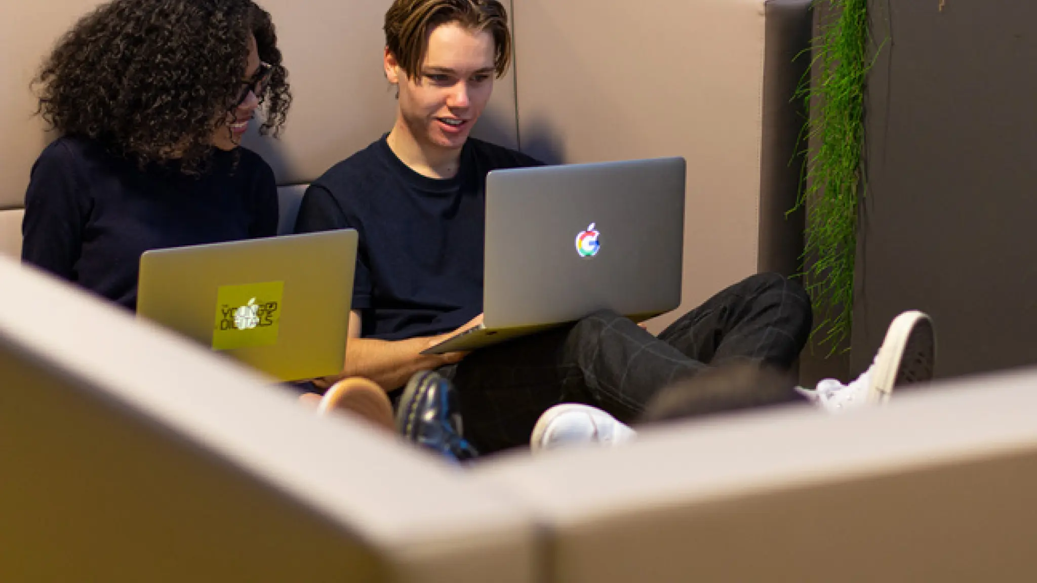 twee jongeren zitten achter hun laptop