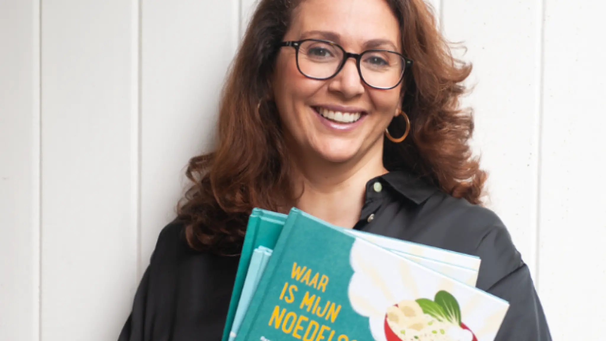 Foto van Chafina, ze lacht in de camera en houdt drie boeken vast. Fotograaf: Bonnita Postma