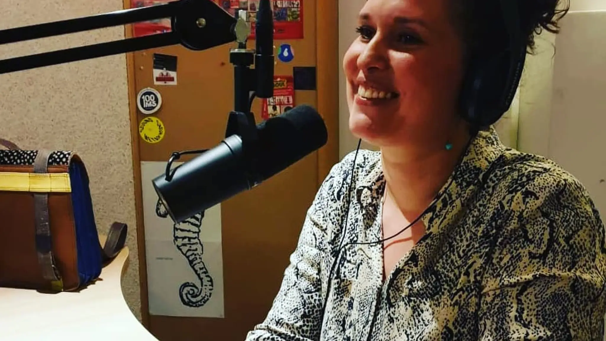 De presentator van deze podcast, Zoë Papaikonomou, zit achter een microfoon.